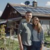 Fiatal pár a napelemes házuk előtt áll.
